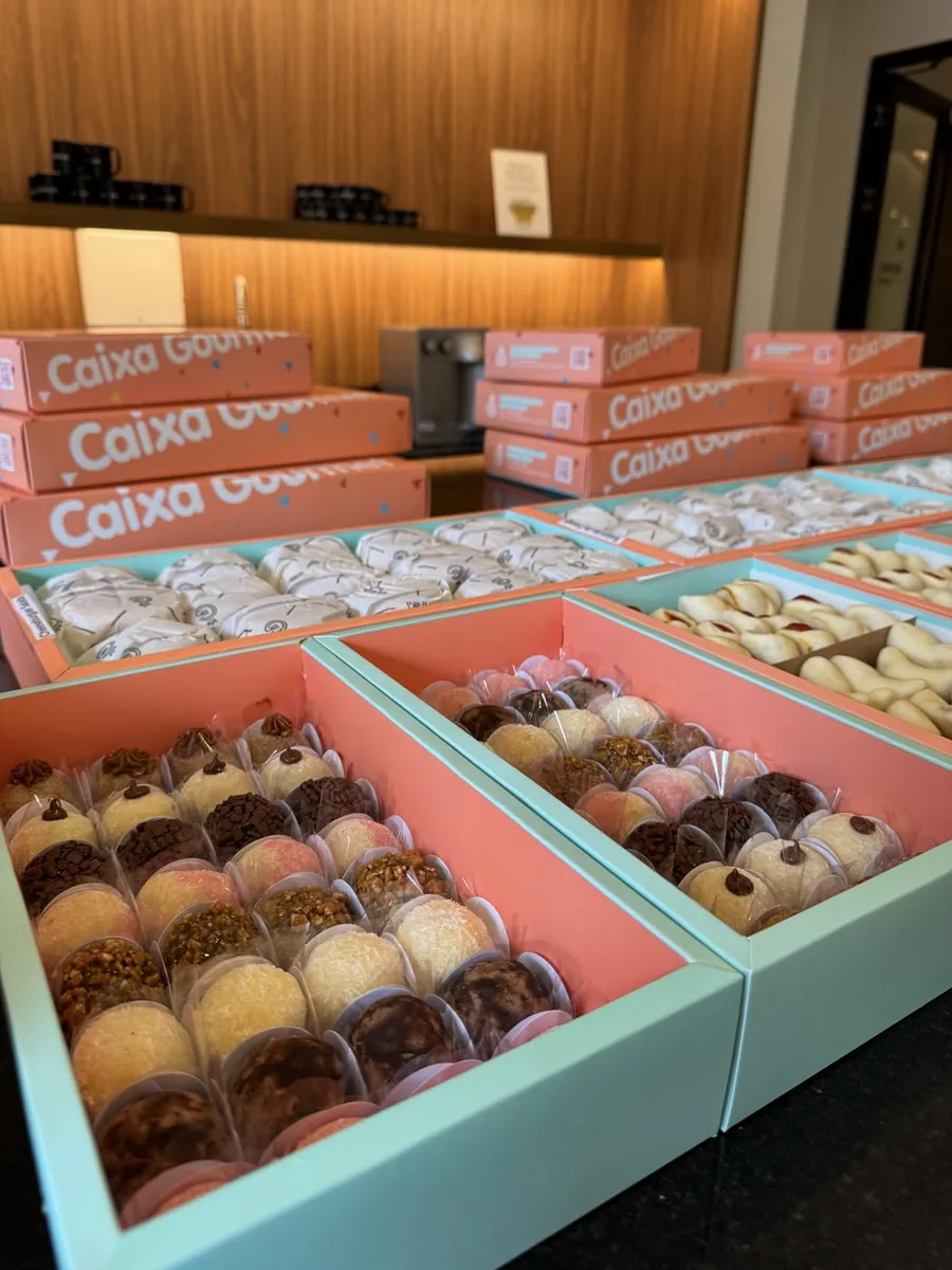 Close de caixa Caixa Gourmet com brigadeiros gourmet e doces variados ao centro da composição.